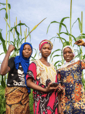 three african women posing in a field